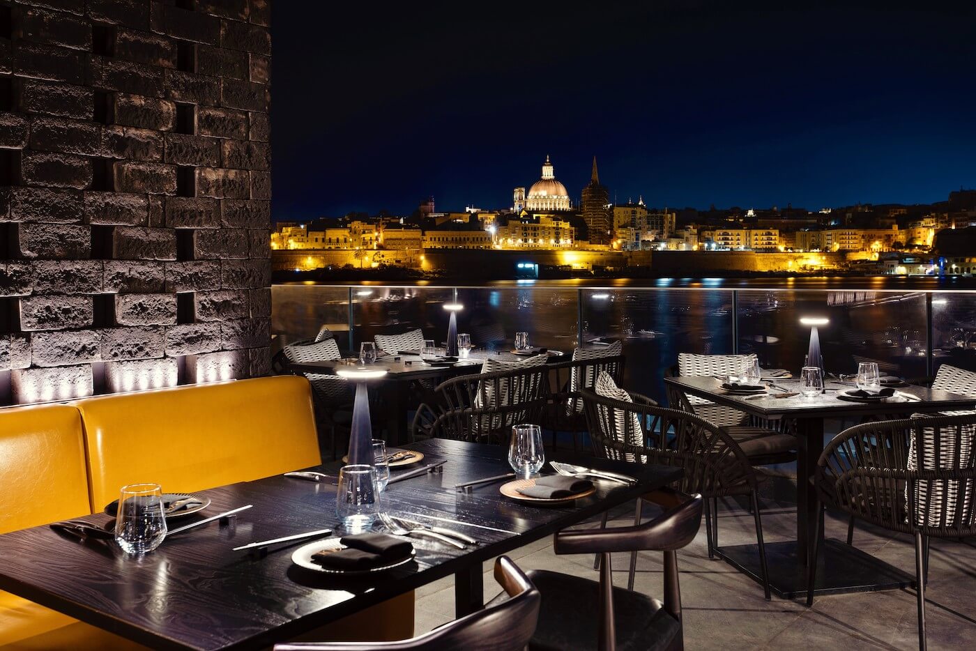 Elegant outdoor seating, city lights sparkle across waterfront