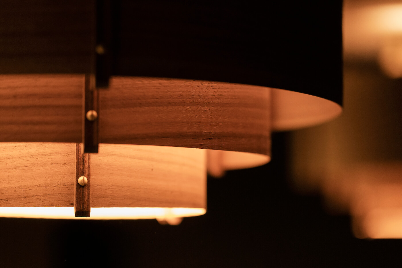 Wooden pendant lampshades glow warmly, creating a cozy and modern ambiance with soft curves.